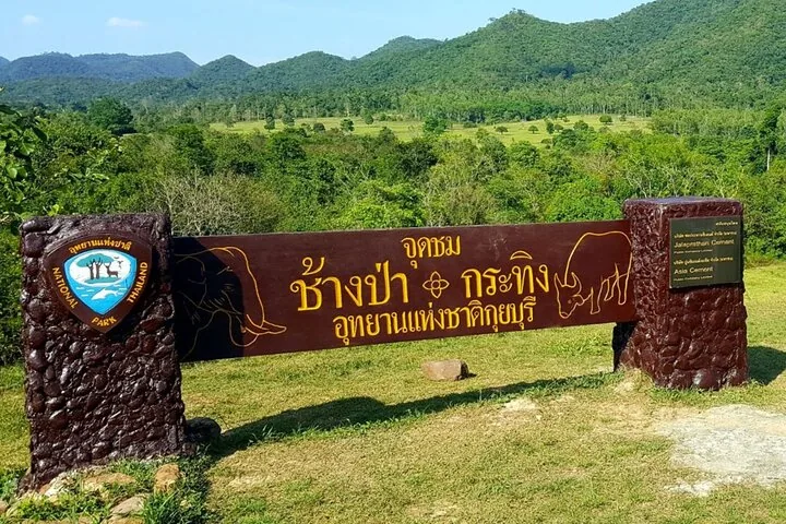 Eingangsschild des Kui-Buri-Nationalparks mit Blick auf ein malerisches grünes Tal.